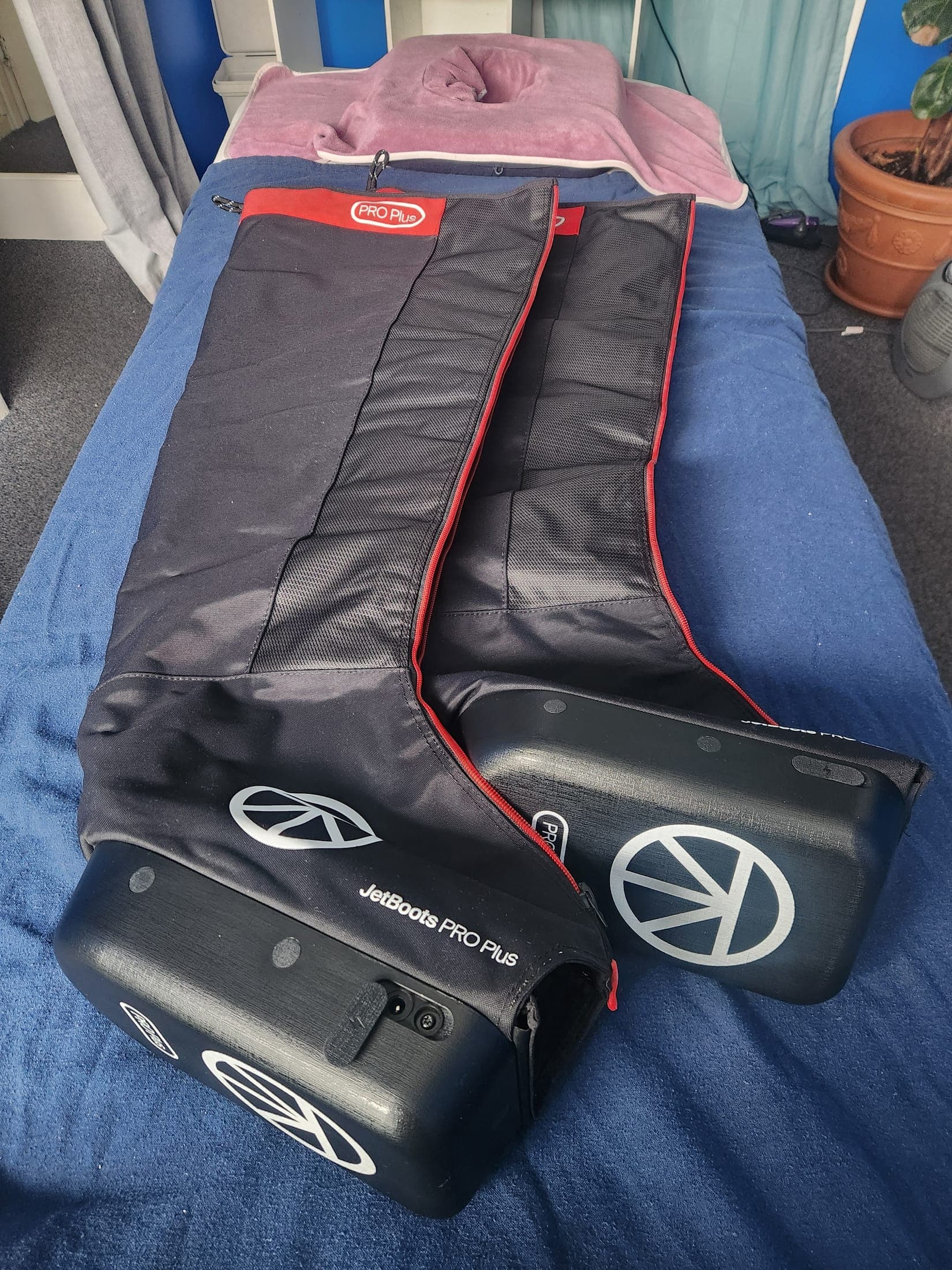 Pair of JetBoots Pro Plus compression boots laid out on the treatment table, one open showing the inner lining